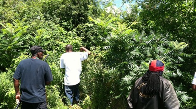 Men scour the woods behind an East Cleveland civic center July 24.