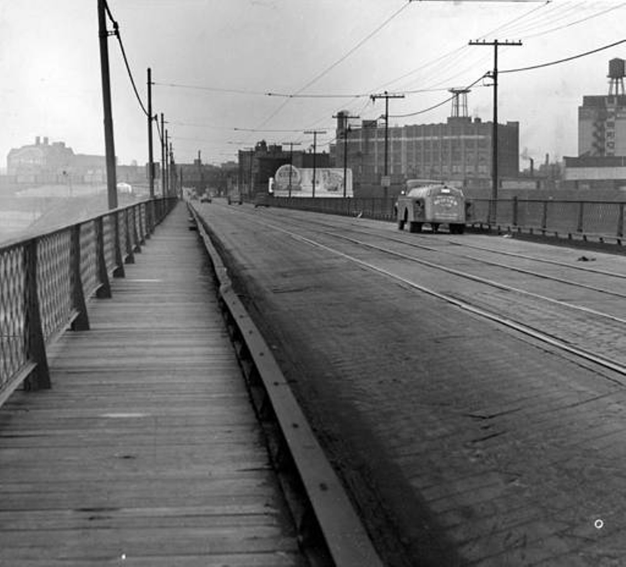 Shows the the deck of the East 34th Street Bridge in Cleveland, Ohio, in 1948. The sidewalks and trolley car tracks are visible. The traffic is light.