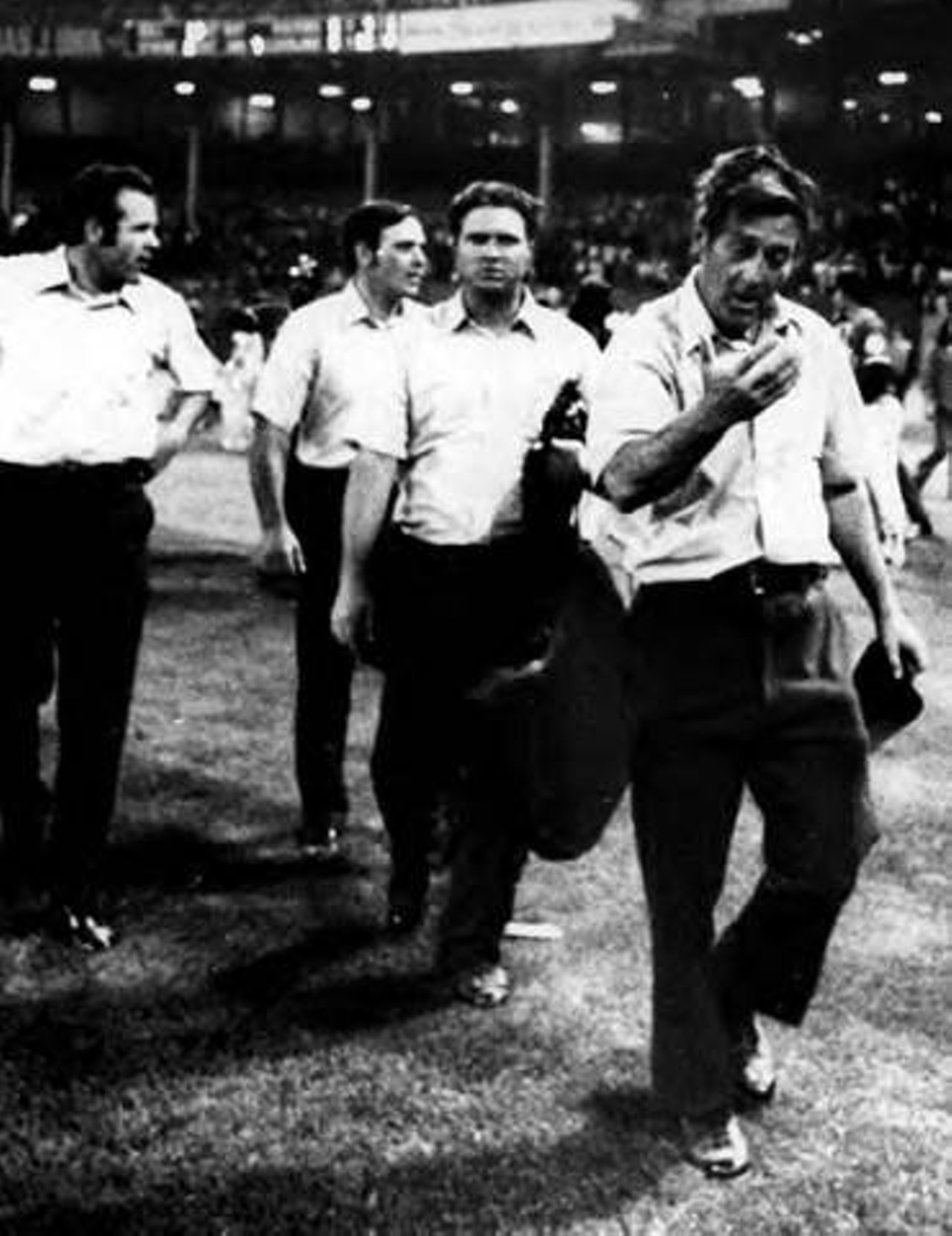 Crew chief Nestor Chylak leads his umpires off the field during the infamous Ten Cent Beer Night game at Cleveland Municipal Stadium. 1974