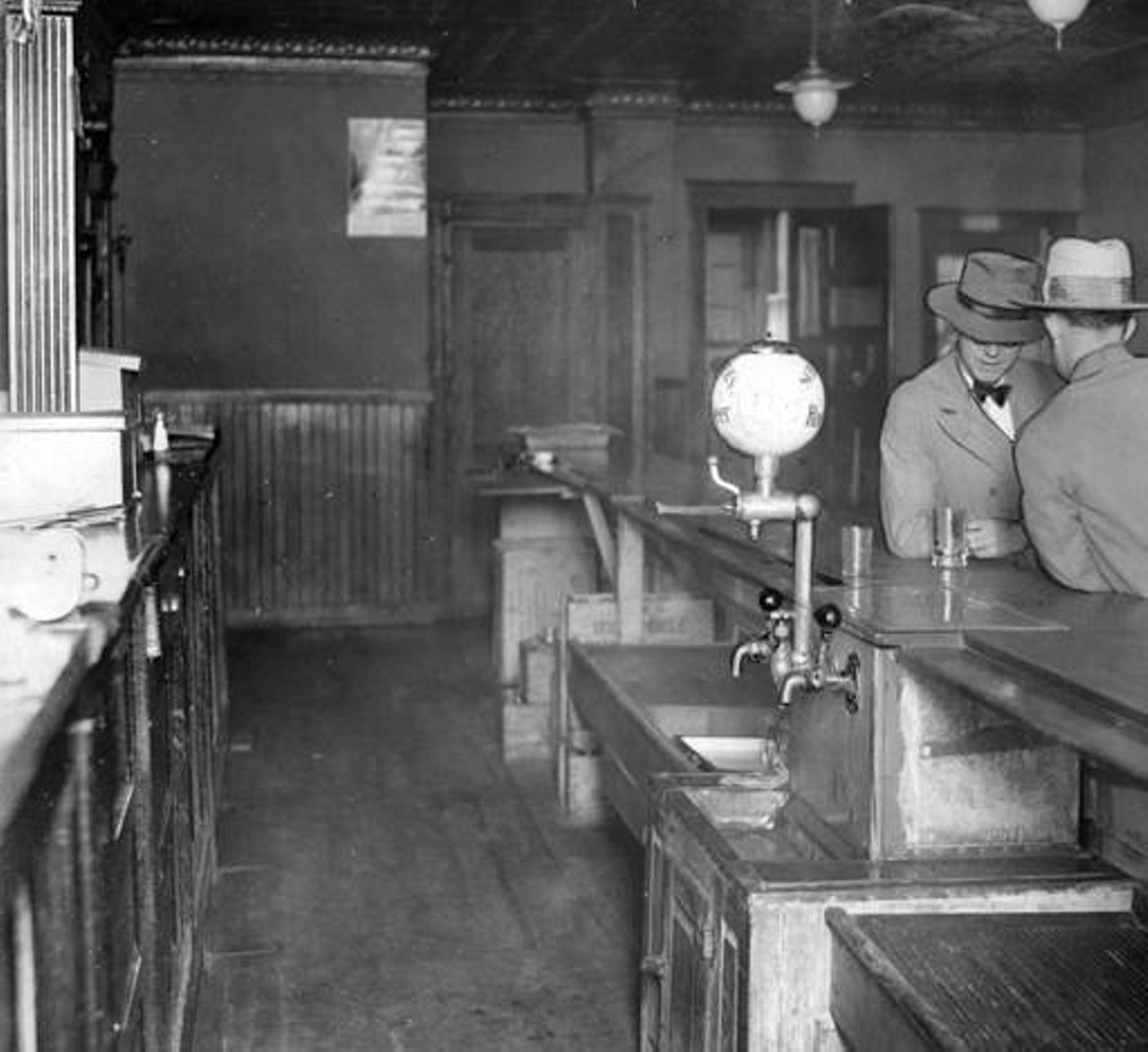 Two men stop in for a drink at empty bar on Waterloo Avenue during Prohibition.