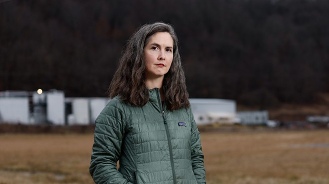 COSHOCTON, OH — JANUARY 25: Lucy Bryan Malenke, a freelance writer and local resident, with the white buildings and tanks of the Buckeye Brine injection facility on Airport Road in the background, January 25, 2024, in Coshocton, Ohio.