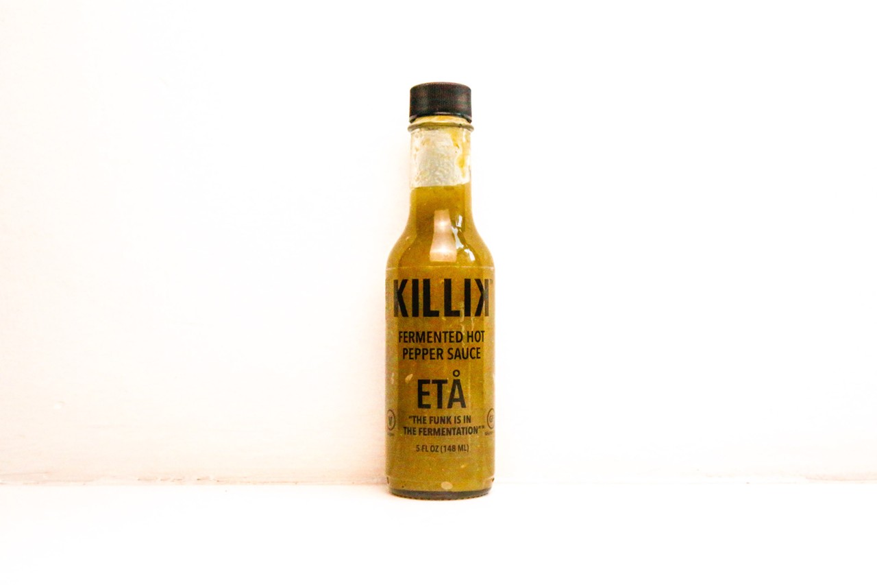Killik
Look: In the ETA, a clear glass bottle with bold black text contains an olive-colored sauce.
Background: Mike Killik and his father both suffered heart attacks within a week of each other. Only the younger Killik survived. To cut back on his sodium intake, Mike began experimenting with fermented hot sauces, which contain less sodium than conventional hot sauces when properly made. It didn’t take long for the former restaurant veteran to land on a winning formula. 
“Seeing how great chefs work, I learned to keep things simple,” he explains. “I didn’t want to overwork and overprocess them; I wanted to make it as scratch as we can.”
Killik’s straightforward recipe starts with poblanos, jalapenos, onion and garlic, which are fermented in brine, blended and bottled. Along with the green ETA, Killik crafts red-hued ZETA and DELTA varieties, all made at Cleveland’s Hildebrandt Building.
Tasting notes: Like most fermented hot sauces, ETA has an unmistakable funkiness that develops in the process. But the pasteurization process tampers that down, along with the heat level, which is modest. It’s a loose but slightly chunky product that straddles the fence between salsa and sauce.  
Uses: Eggs, pizza, grilled fish, fish tacos, roasted chicken
Heat index: 2/10
Find it at: Dean Supply, Market District, Lakewood Hardware, Juneberry, killikhsc.com