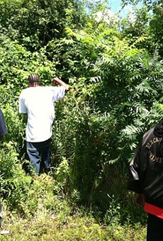 Men scour the woods behind an East Cleveland civic center July 24.