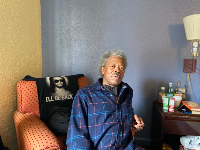 Abel Currie, 63, sits in his hotel room in May. It’s been a relief for him to have space to quarantine safely as he searches for a permanent apartment.
