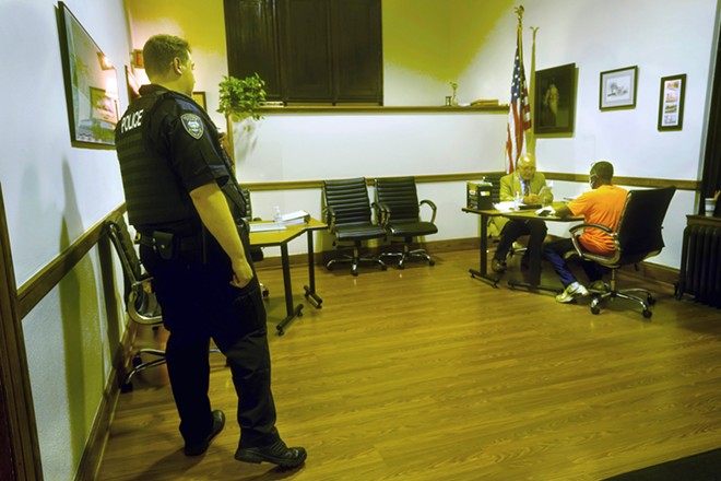 Prosecutor Tom Hanculak, center, speaks to a person who suffered a traffic violation while a Bratenahl police officer oversees the proceedings October 11, 2022.  – Gus Chan for The Marshall Project