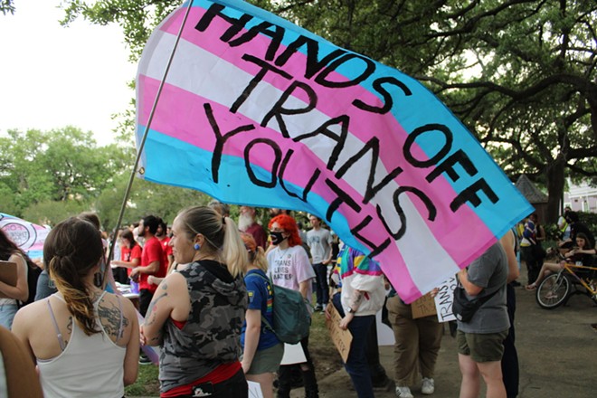 A transgender Pride flag is covered with the words “Hands Off Trans Youth.” - (Photo by Greg LaRose/Louisiana Illuminator/States Newsroom)