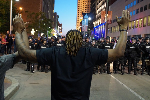 A protester stands before riot police in May, 2015, on the night of the Michael Brelo portests. - Sam Allard / Scene